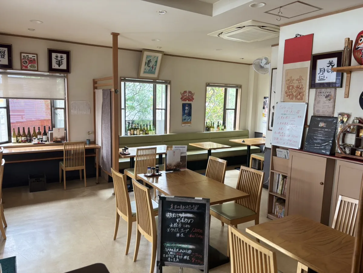 木のテーブルと窓ぎわのソファ席が並ぶ萬万亭の店内